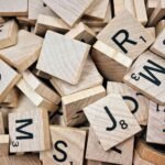 Piezas de madera con letras y números de un juego de palabras, apiladas en un montón.