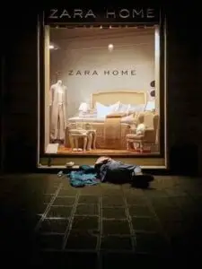 Vitrine da loja Zara Home com decoração de interiores e uma pessoa deitada na calçada em frente.