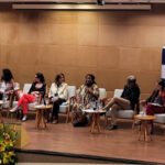 Grupo de pessoas sentadas em um painel de discussão durante um evento em um auditório.