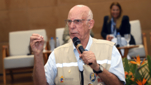 Pe. Lancellotti usando um colete claro e segurando um microfone durante uma apresentação em um evento.
